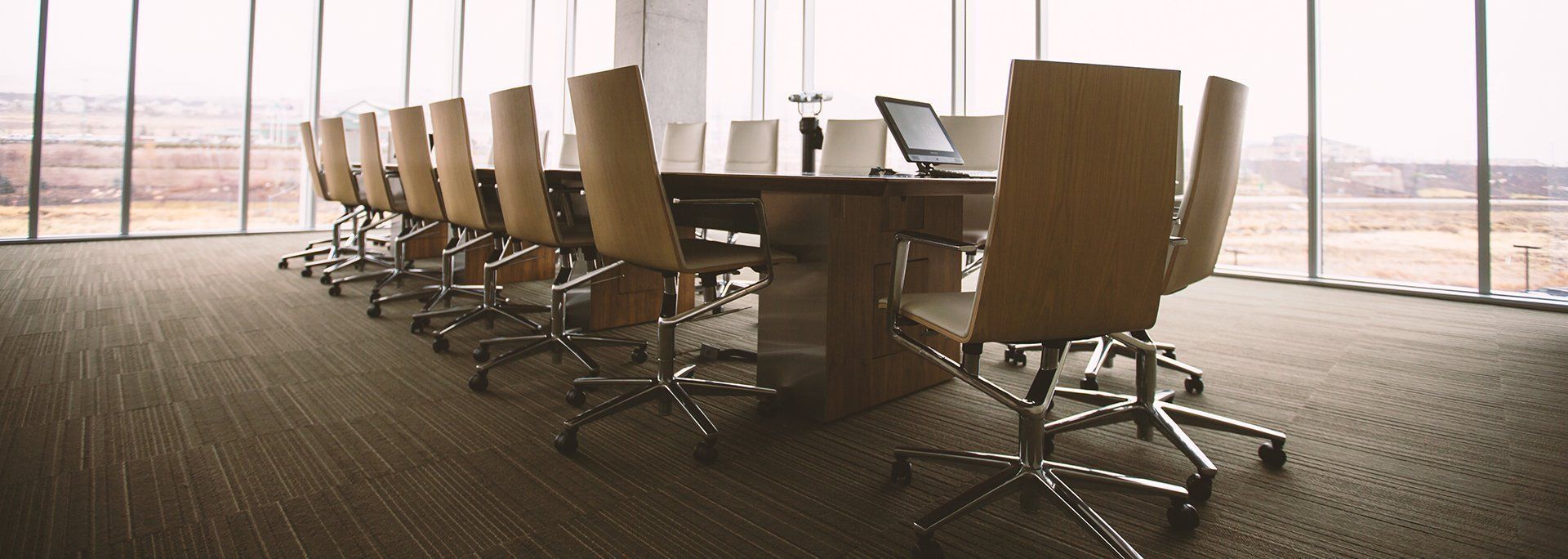 A conference room with a long table and chairs and a lot of windows.