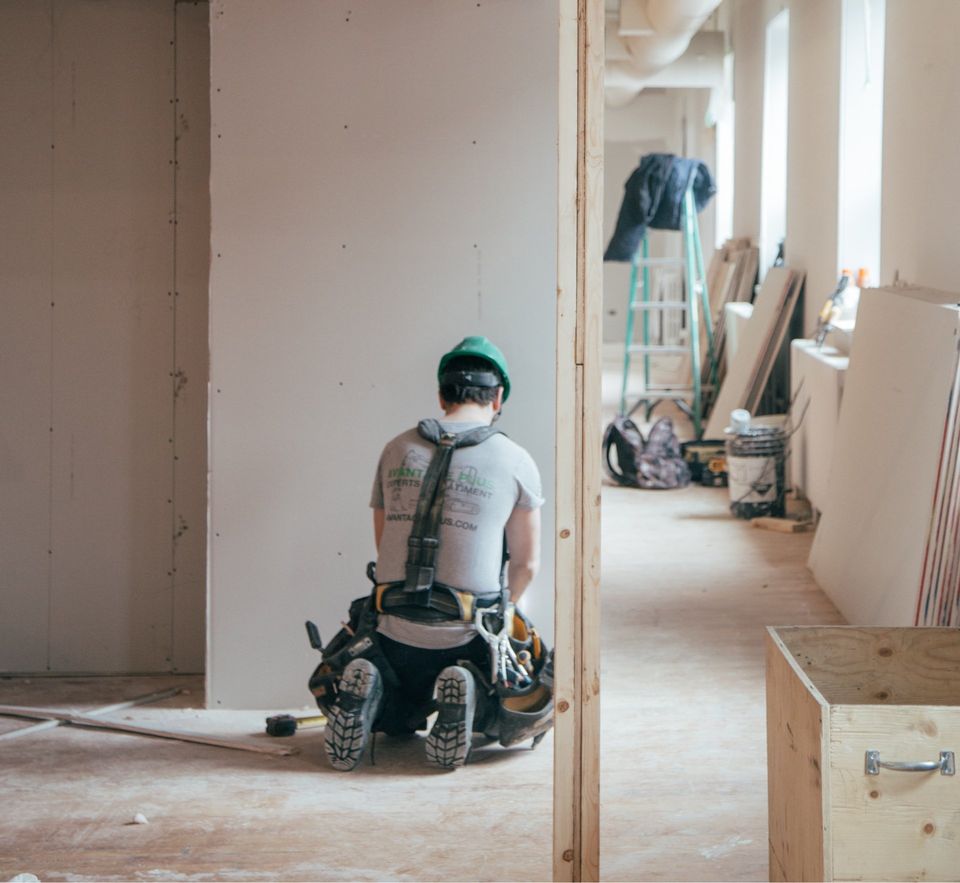 A man is sitting on the floor in a room under construction.