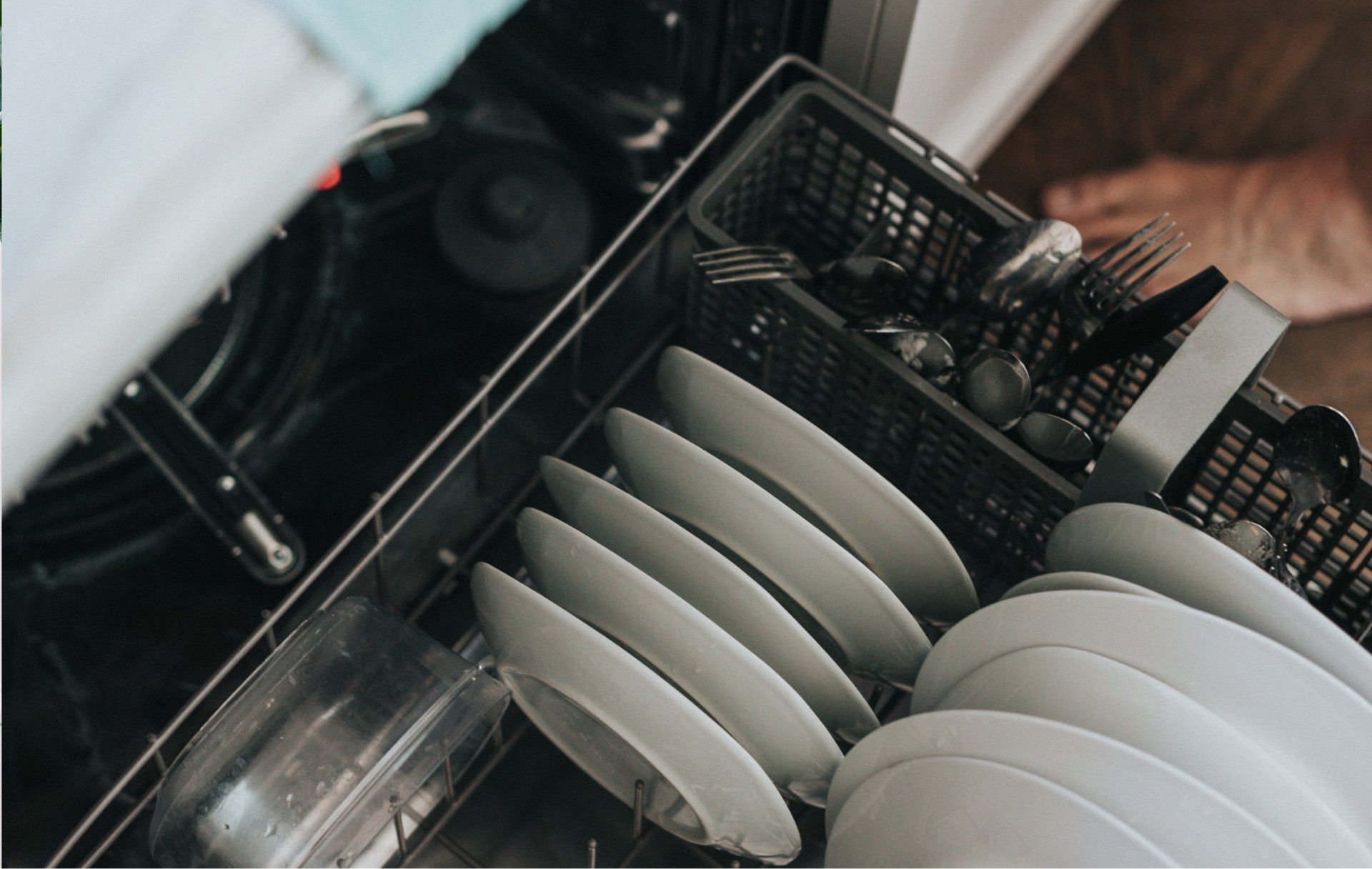 A person is loading dishes into a dishwasher.