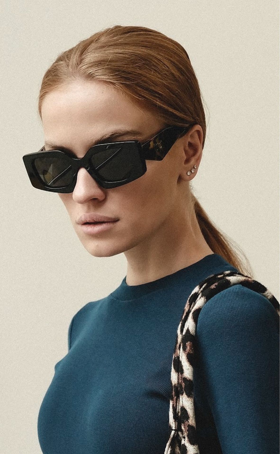 A woman wearing a blue sweater and black sunglasses.