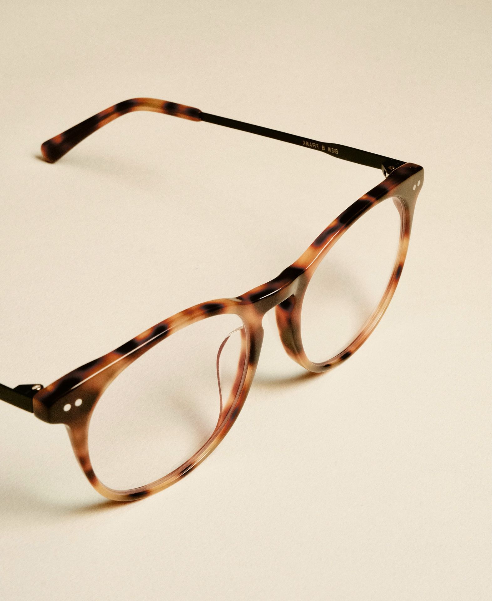 A pair of brown glasses with clear lenses on a white surface