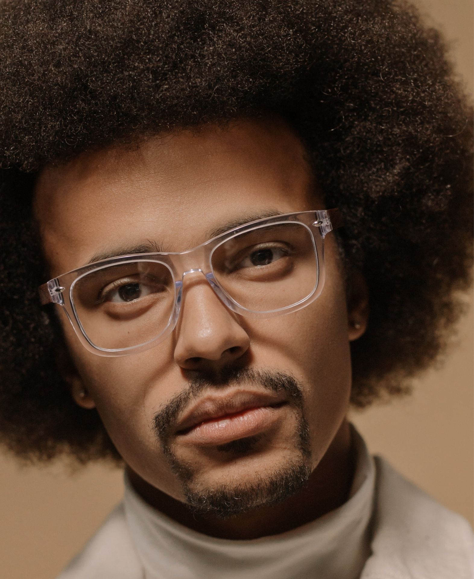A man with an afro wearing clear glasses and a white turtleneck