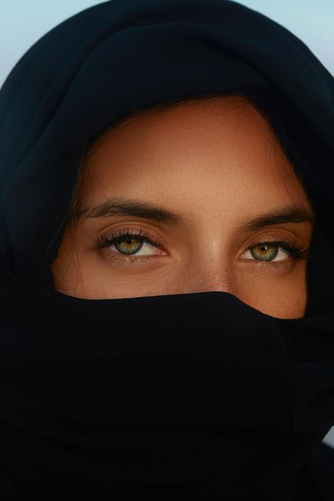 Close-up of a person wearing a black headscarf and face covering, showing only their eyes.