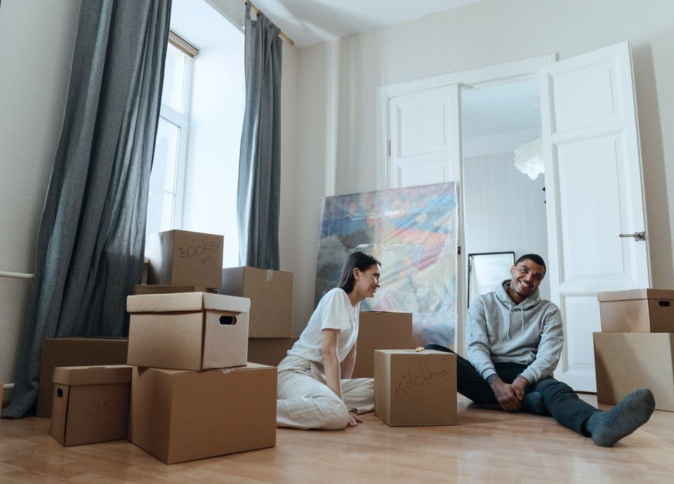 Man and woman sitting while surrounded by move-out boxes