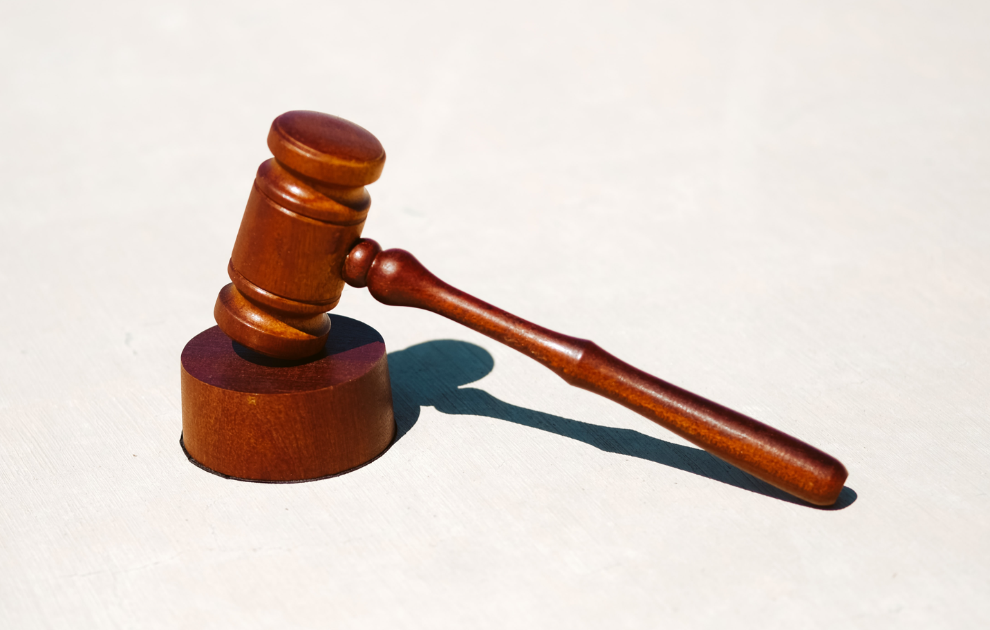 Wooden gavel resting on a wooden block, casting a shadow.