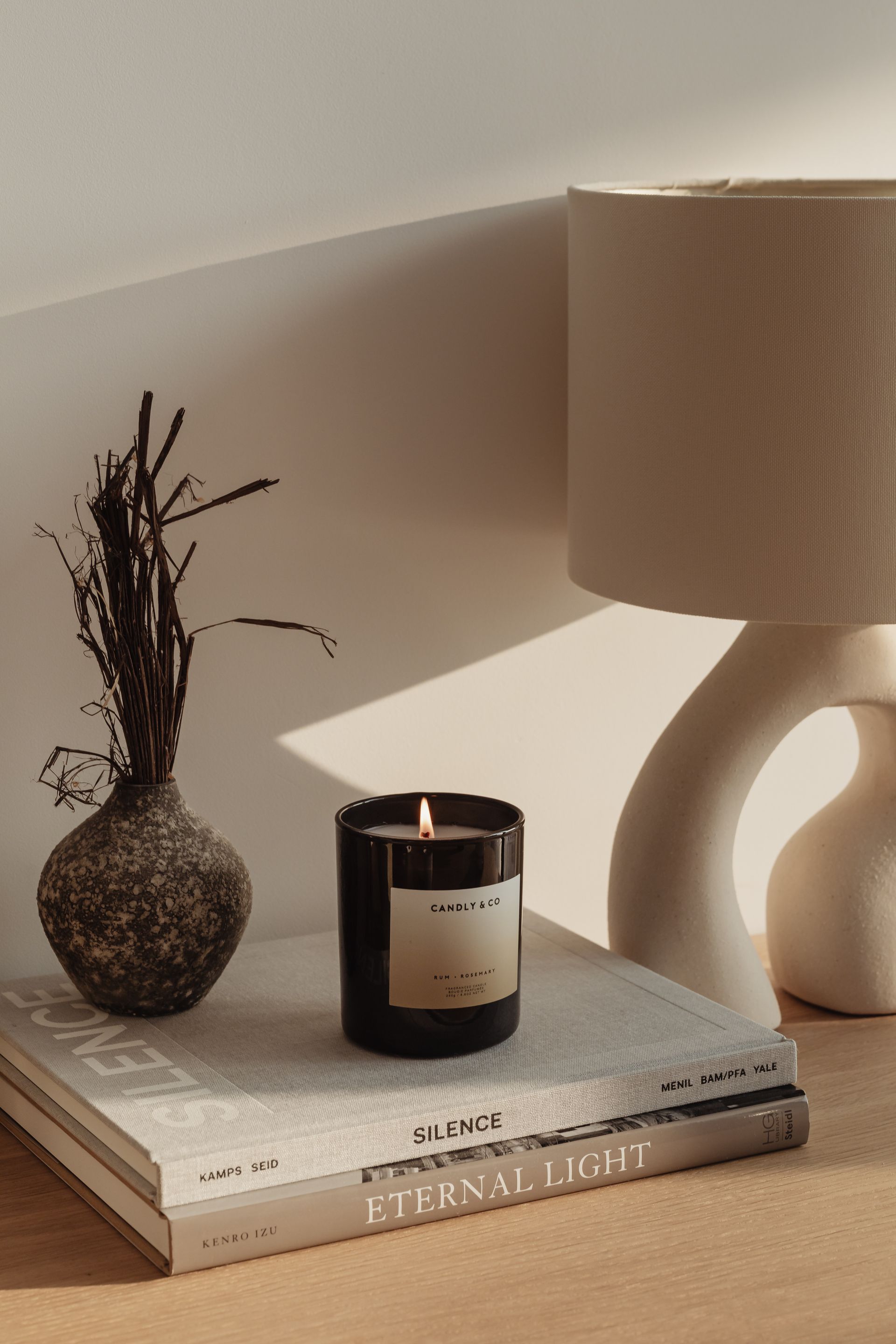 A candle is sitting on top of a stack of books next to a vase.