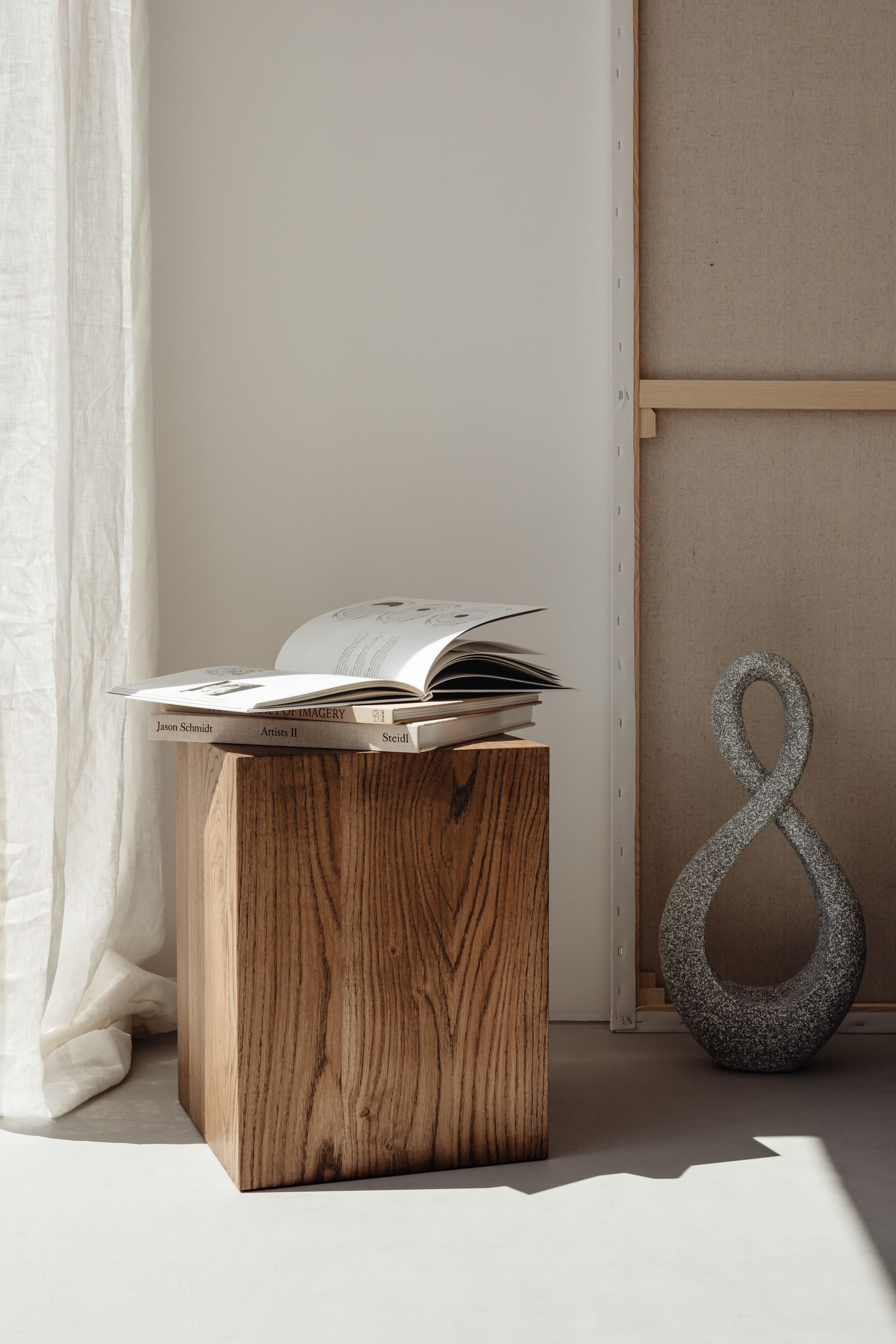 A book is sitting on top of a wooden block in a room next to a window.