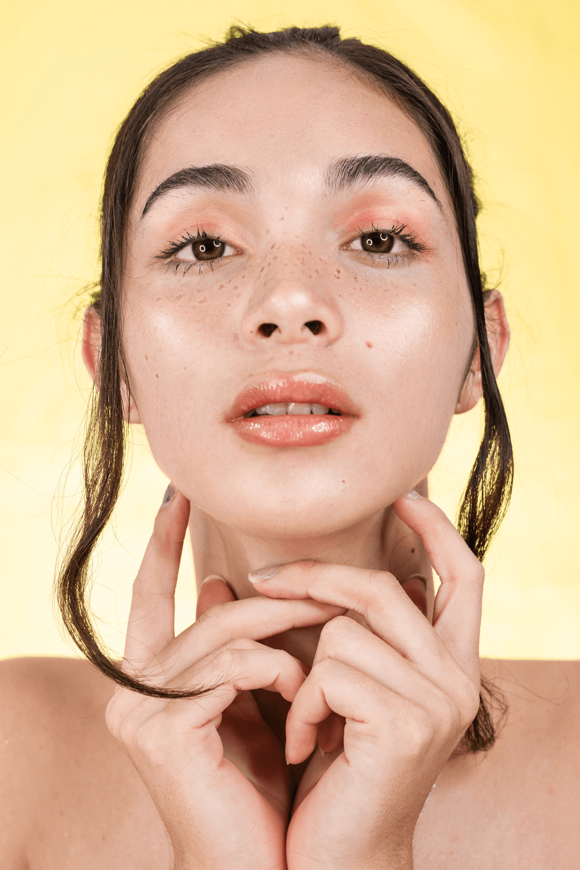 A close up of a woman 's face with her hands on her chin.