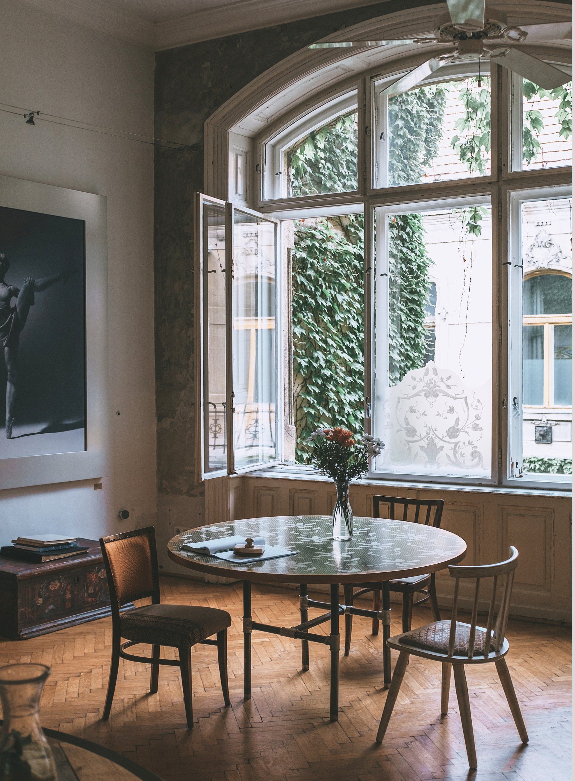 Een kamer met een tafel en stoelen voor een groot raam