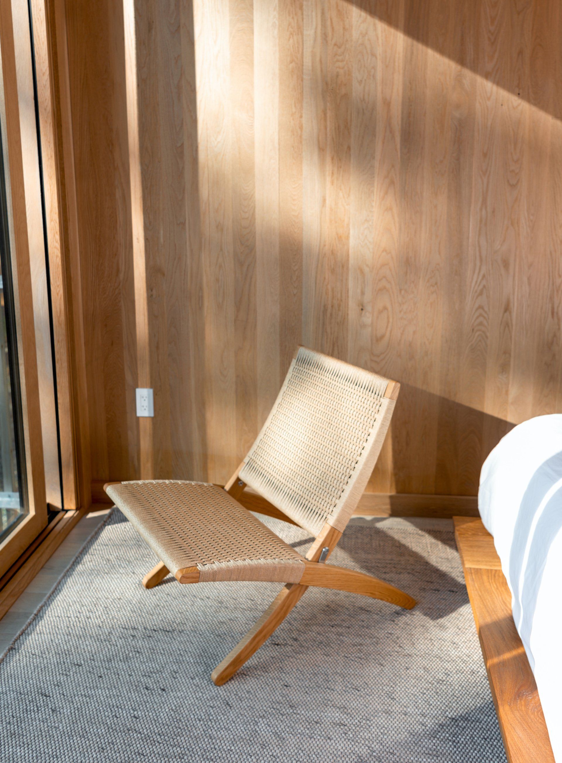 Een houten stoel staat in een slaapkamer naast een bed.