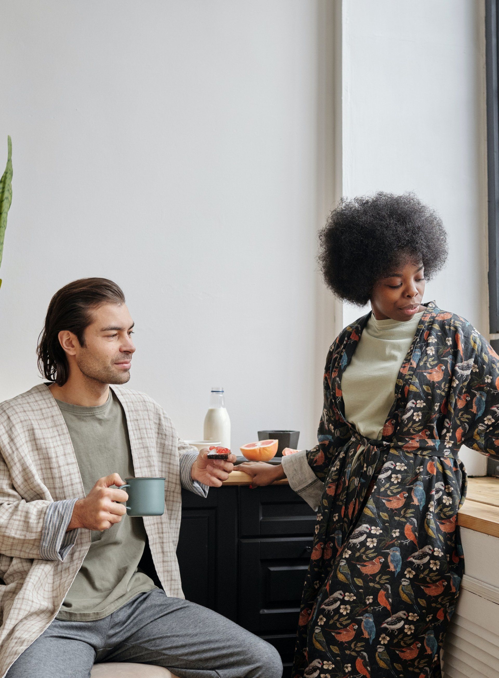 Een man en een vrouw zitten naast elkaar in de keuken koffie te drinken.