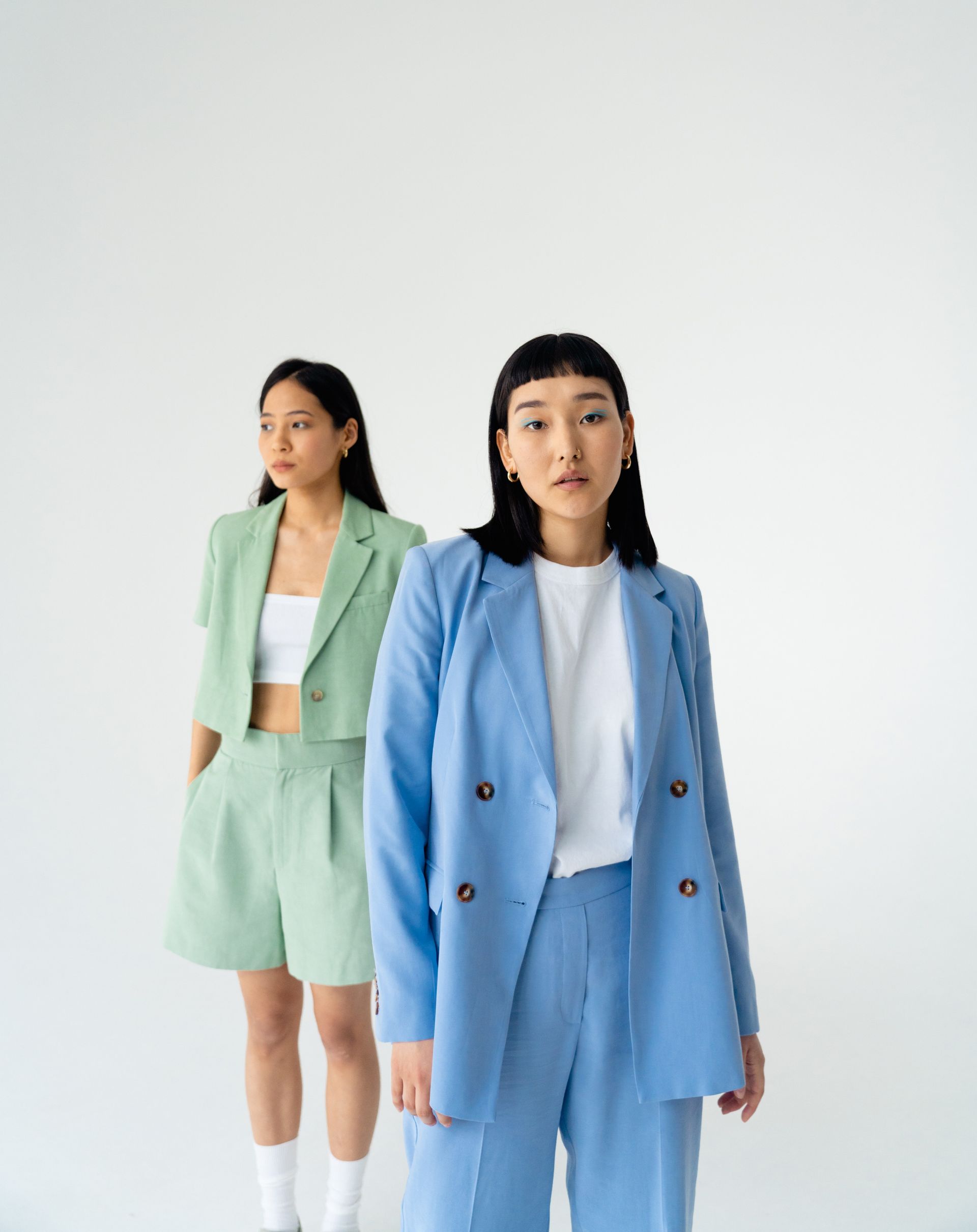 Two women are standing next to each other wearing suits.