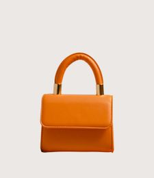Orange handbag with a rounded handle on a light background