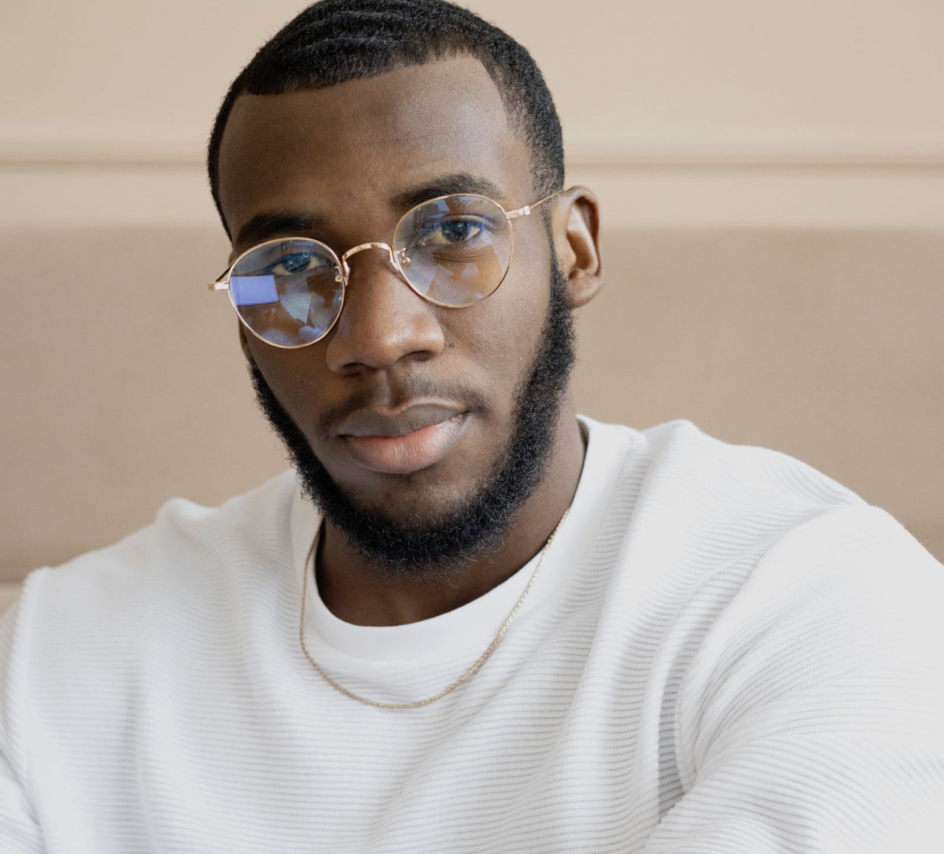 Man wearing glasses and a white sweater looking directly at the camera.