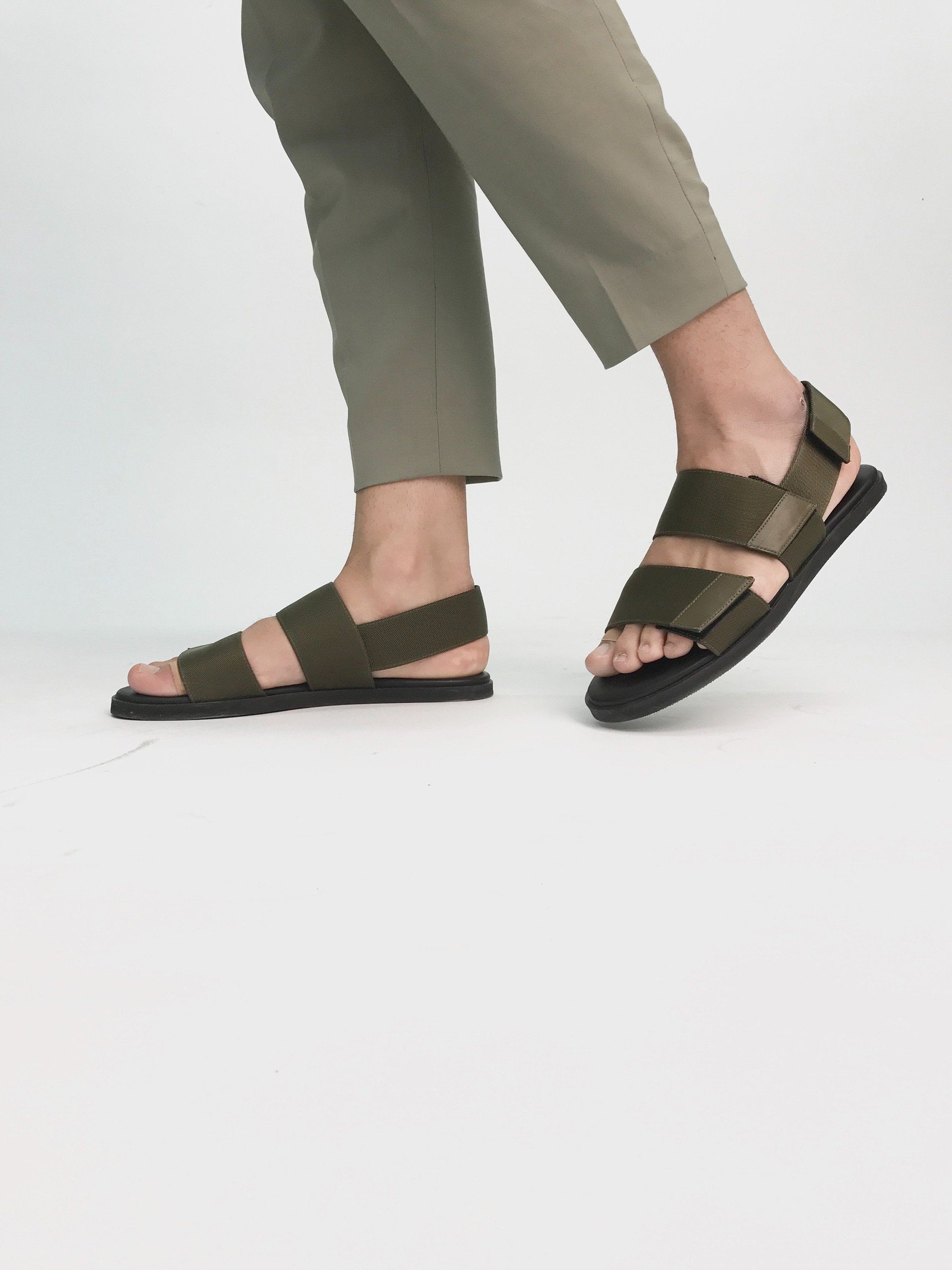 A person is wearing a pair of green sandals.