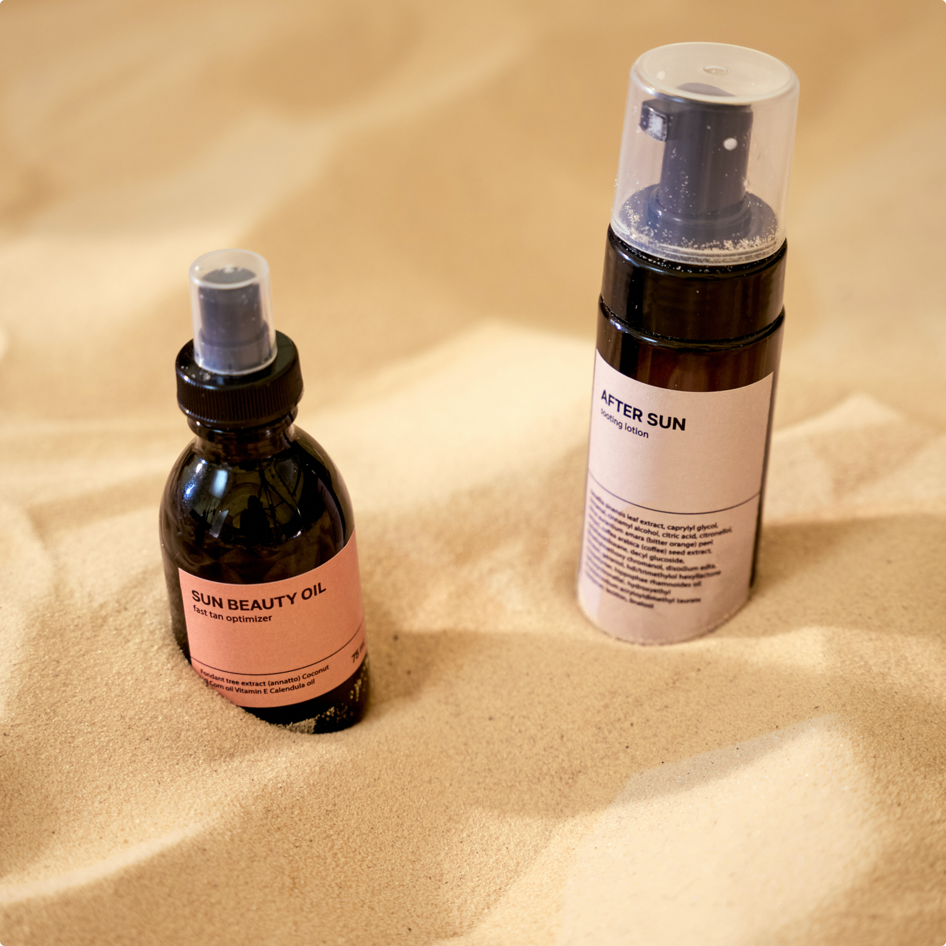 Two dark cosmetic bottles with pink labels on sand.