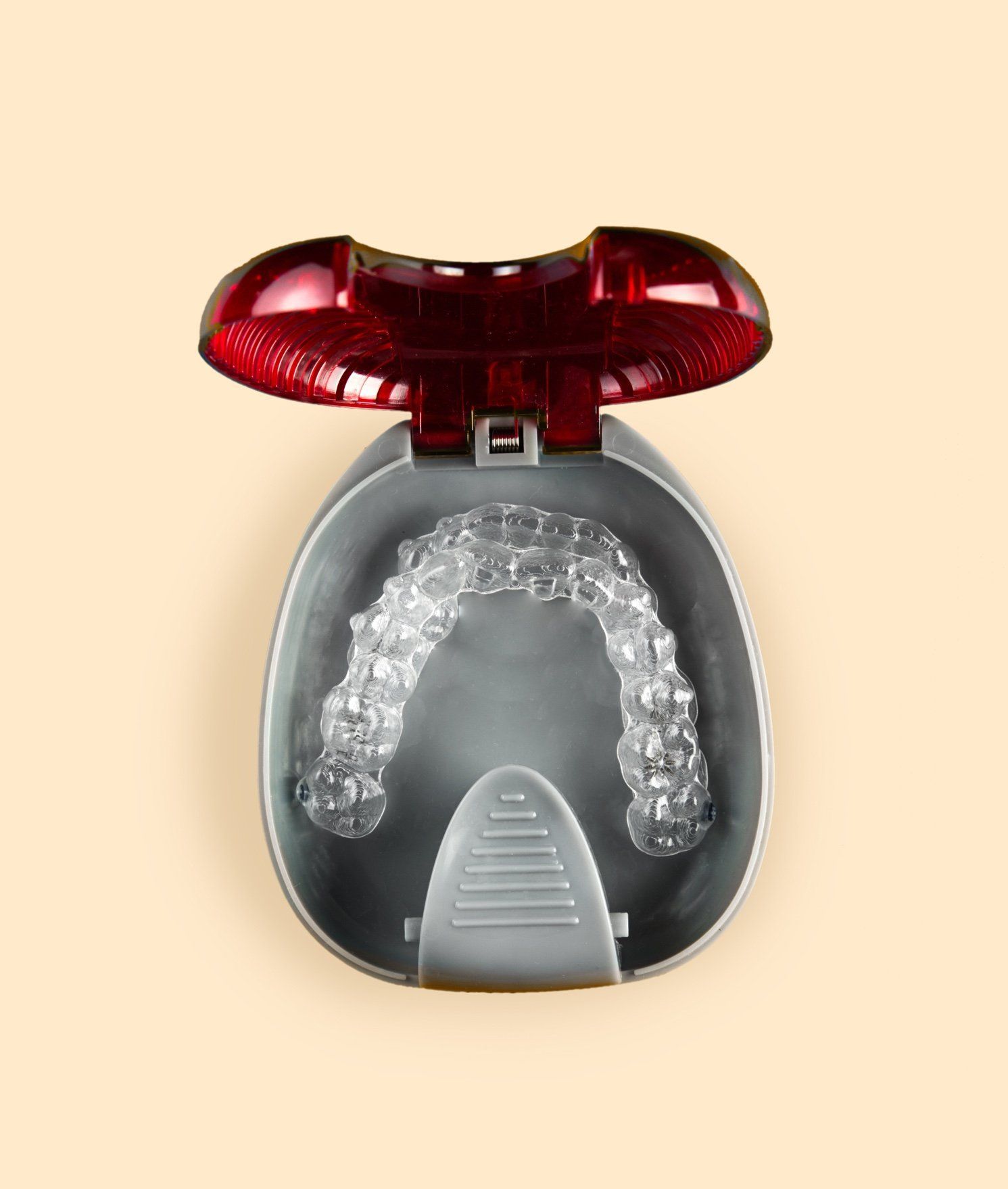 Estuche rojo abierto que contiene alineadores dentales transparentes dentro de una bandeja gris.
