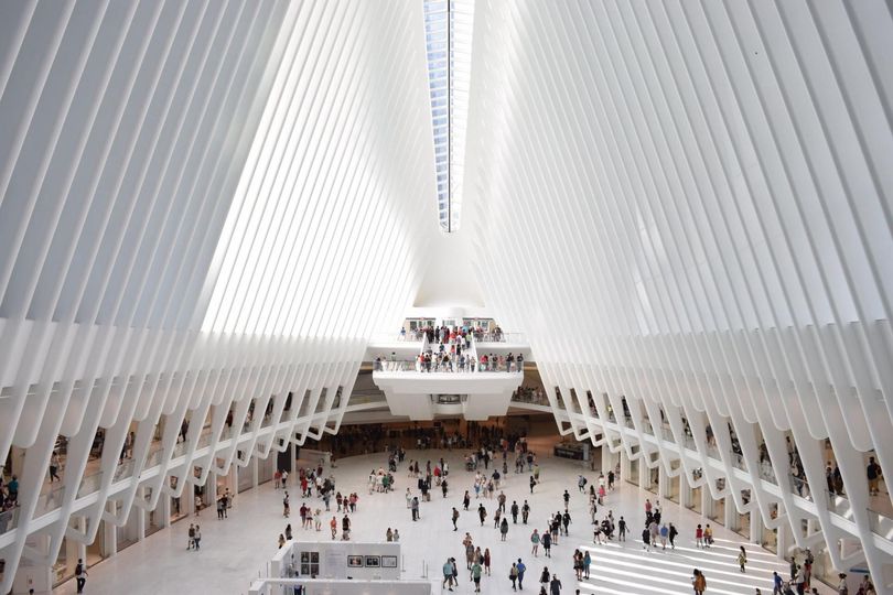Interior of a large, white, modern building with many people walking.
