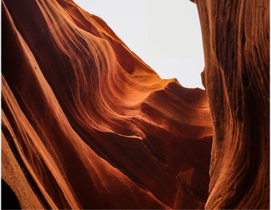 Sandstone canyon walls in shades of red and orange, with light peeking through the top.