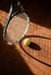 Tennis racket and ball on a clay court with strong shadows.