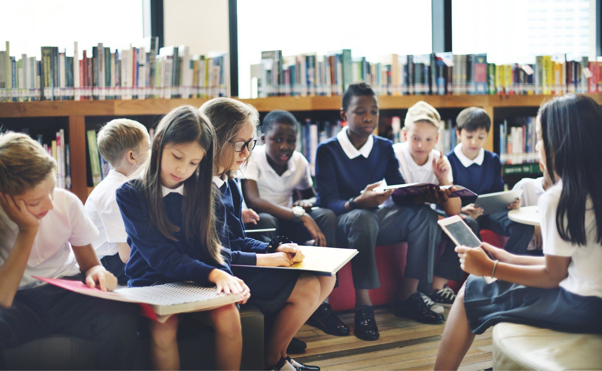 A group of children are sitting in a library reading books.