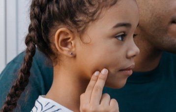 A portrait of a young girl holding her right painful face cheeck due to toothache