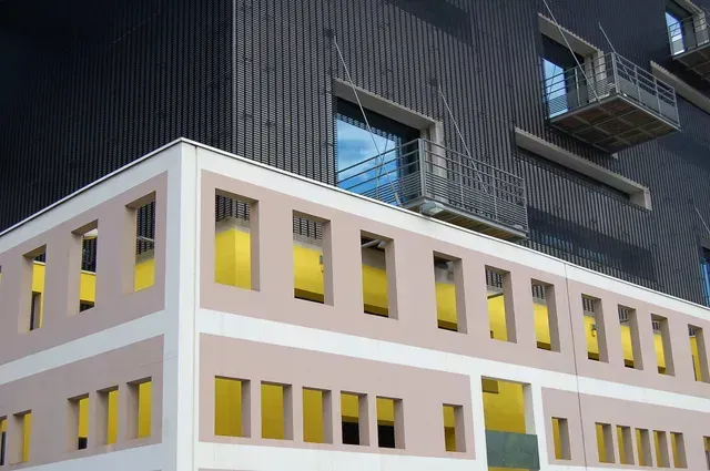 Modern building facade with yellow-lit windows and dark corrugated upper exterior