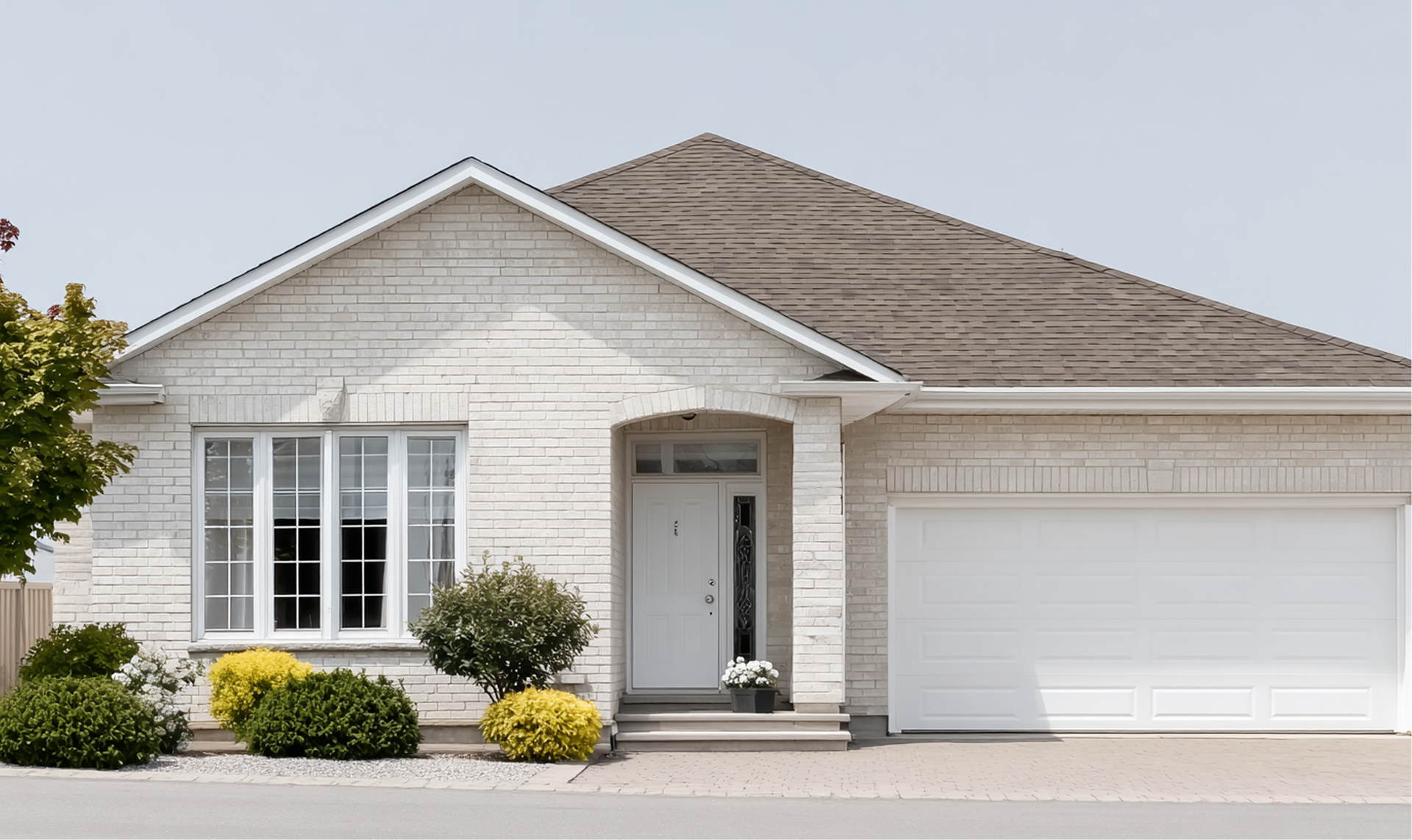 Single-story white suburban house with a two-car garage, front porch, and neatly trimmed shrubs