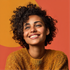 Smiling person in a mustard sweater against an orange background