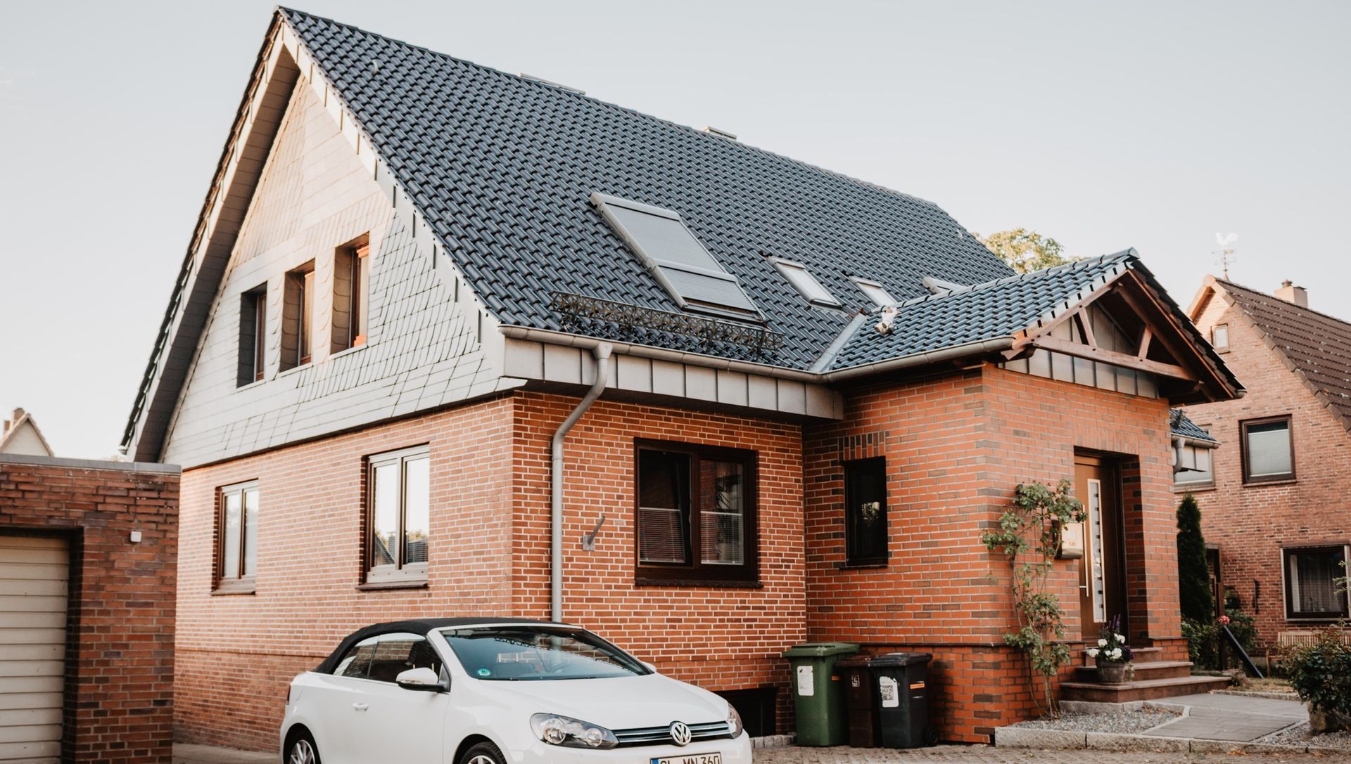 A white car is parked in front of a brick house : KrystalClear : 