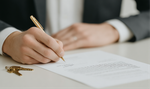 Person signing a document with a gold pen, keys on the table. Person signing a document with a gold pen, keys on the table.