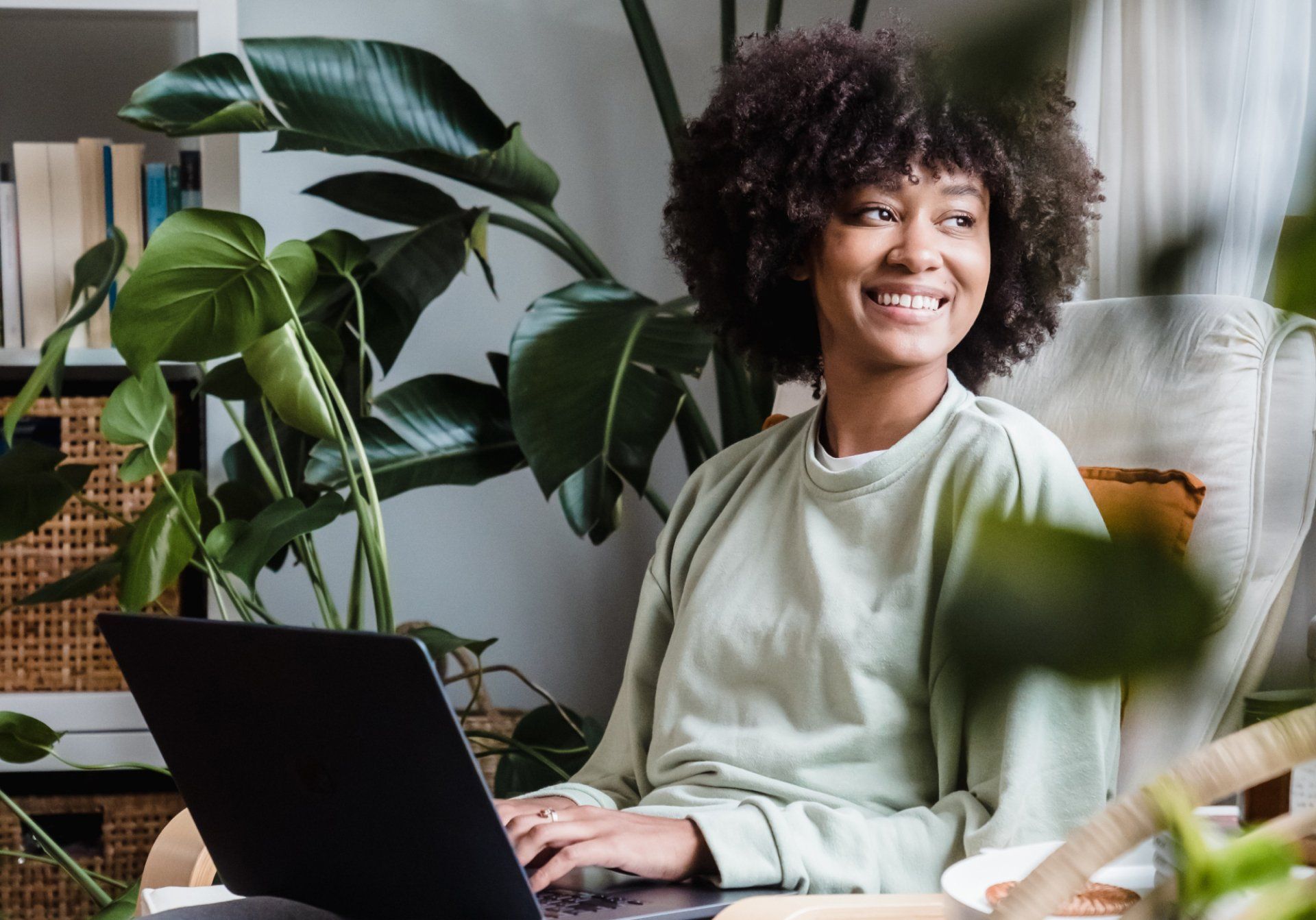 A woman is sitting in a chair using a laptop computer.