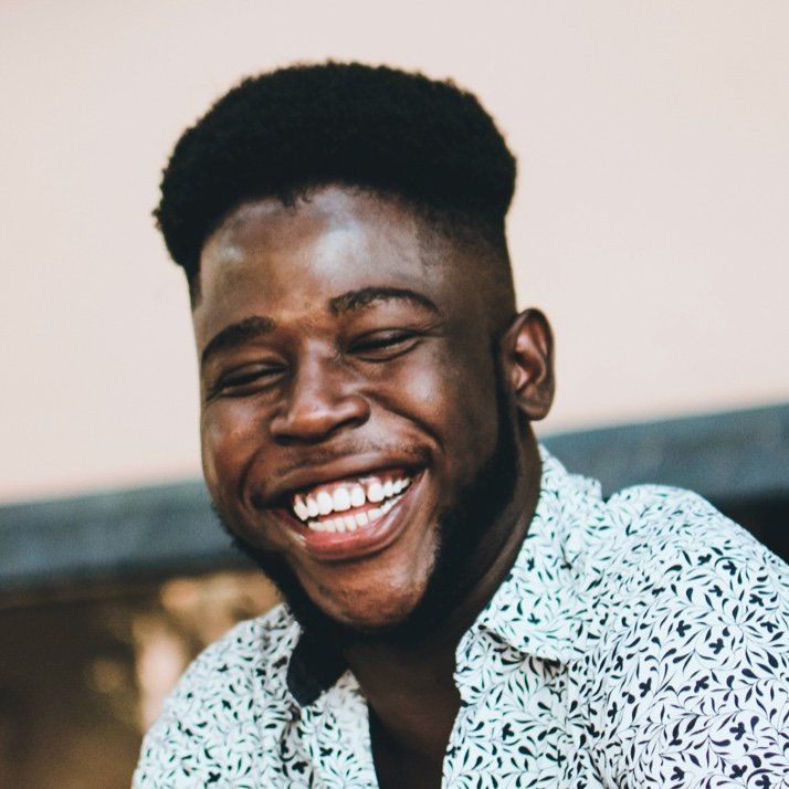 Man smiling widely, wearing a patterned shirt.