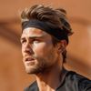 Close-up of a man with a headband, looking off-camera against a blurred desert background