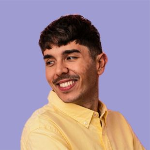 A man with a mustache is wearing a yellow shirt and smiling.