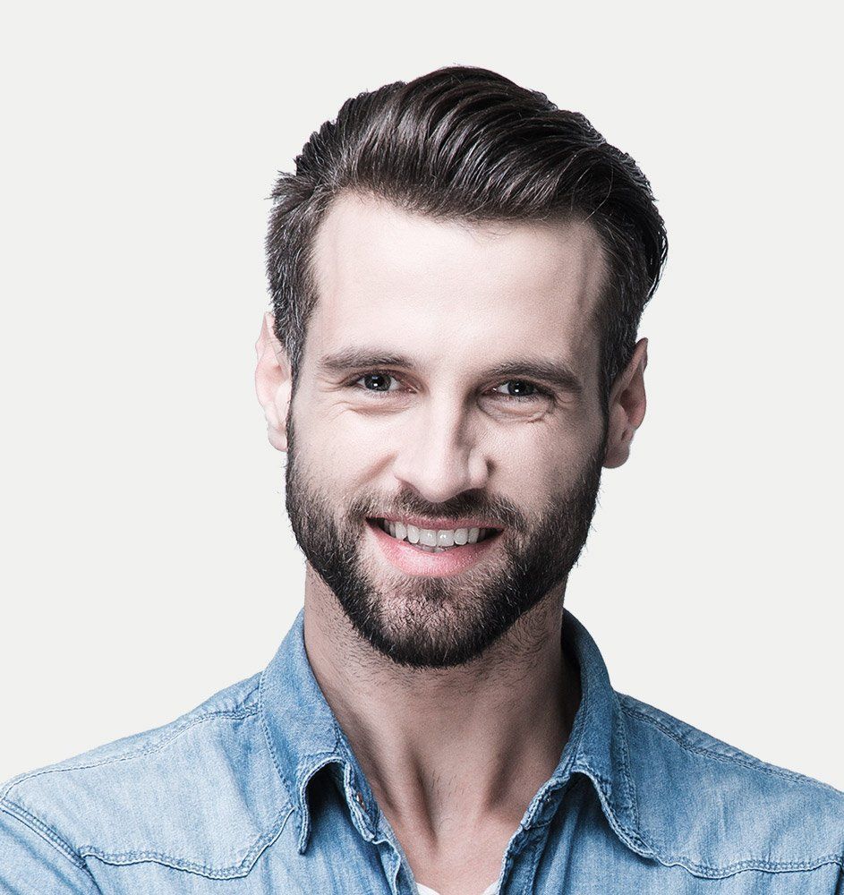 Man with dark hair and beard smiling, wearing a blue denim shirt.