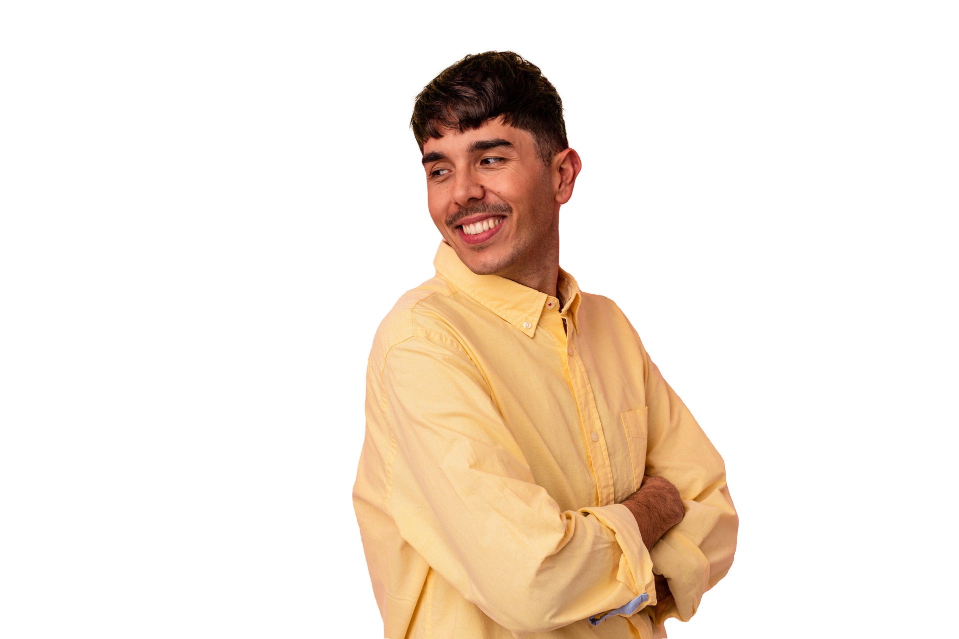 A young man in a yellow shirt is standing with his arms crossed and smiling.
