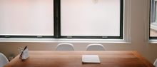 Minimal office table with a notebook and pen in front of two windows