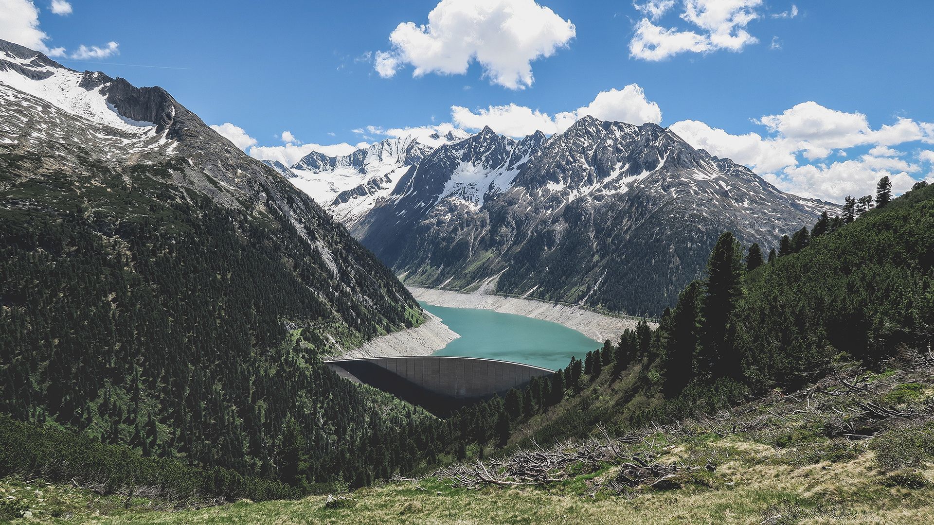 Inmitten der Berge liegt ein von Bäumen umgebener See.