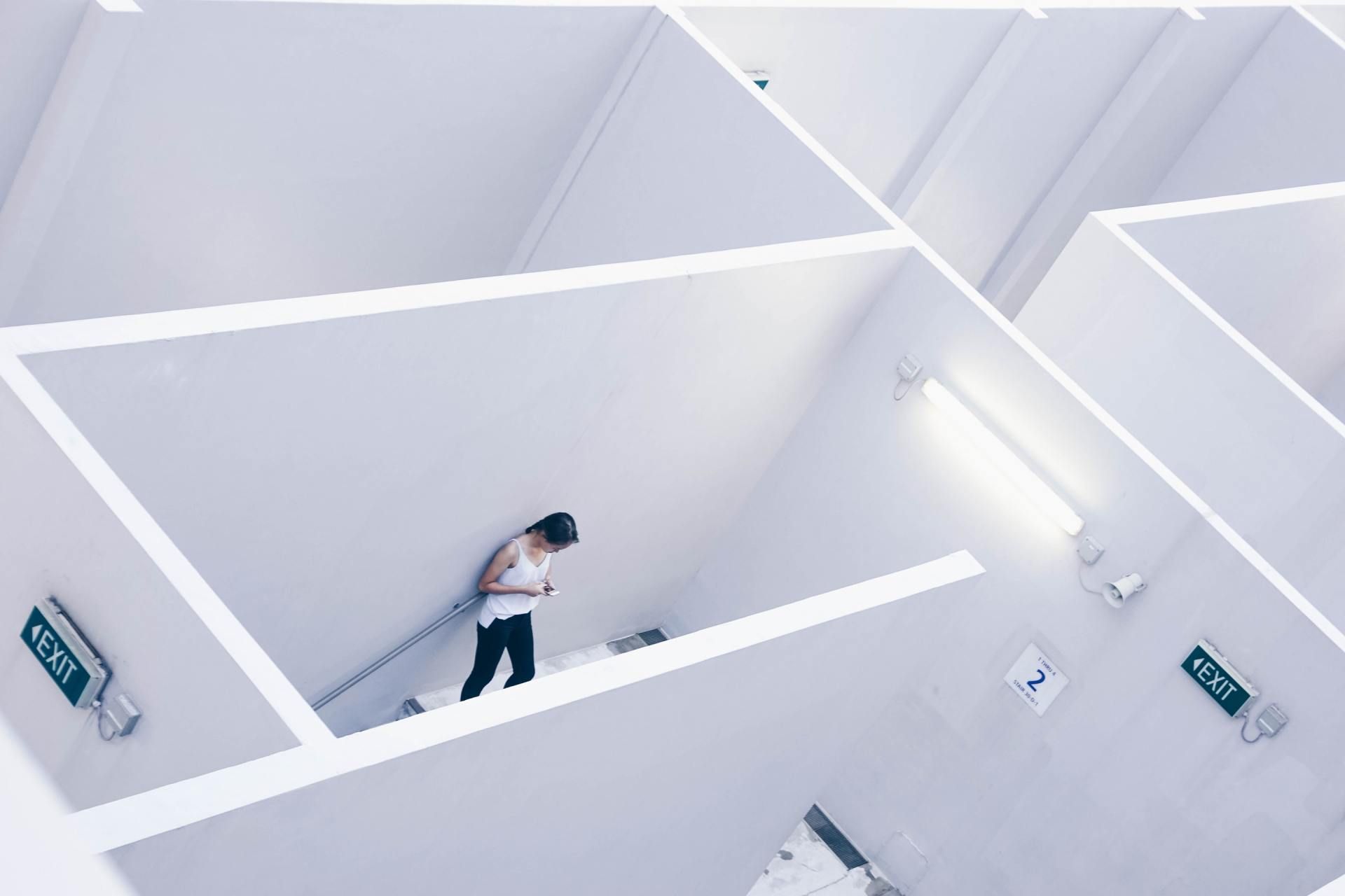 Person walking through a bright white geometric interior with angular walls and fluorescent lights
