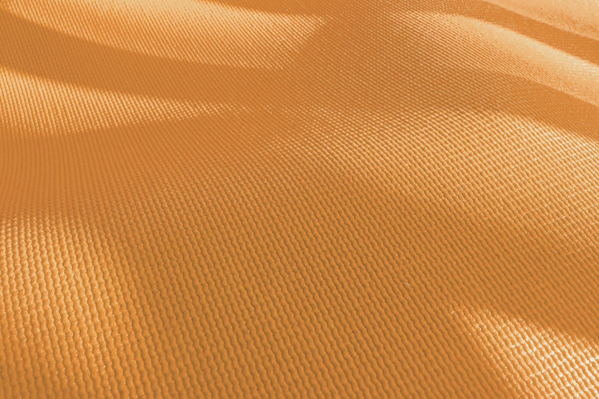 Close-up of orange-tan fabric with visible woven texture, rippling in soft folds.