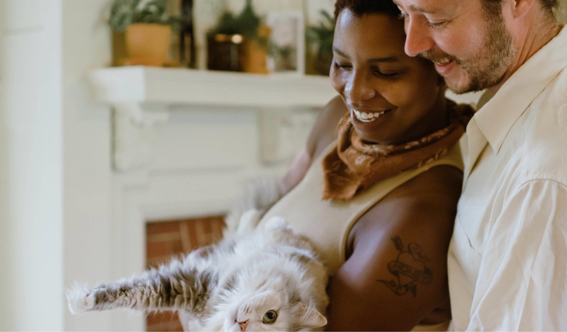 A man and a woman are holding a cat in their arms.
