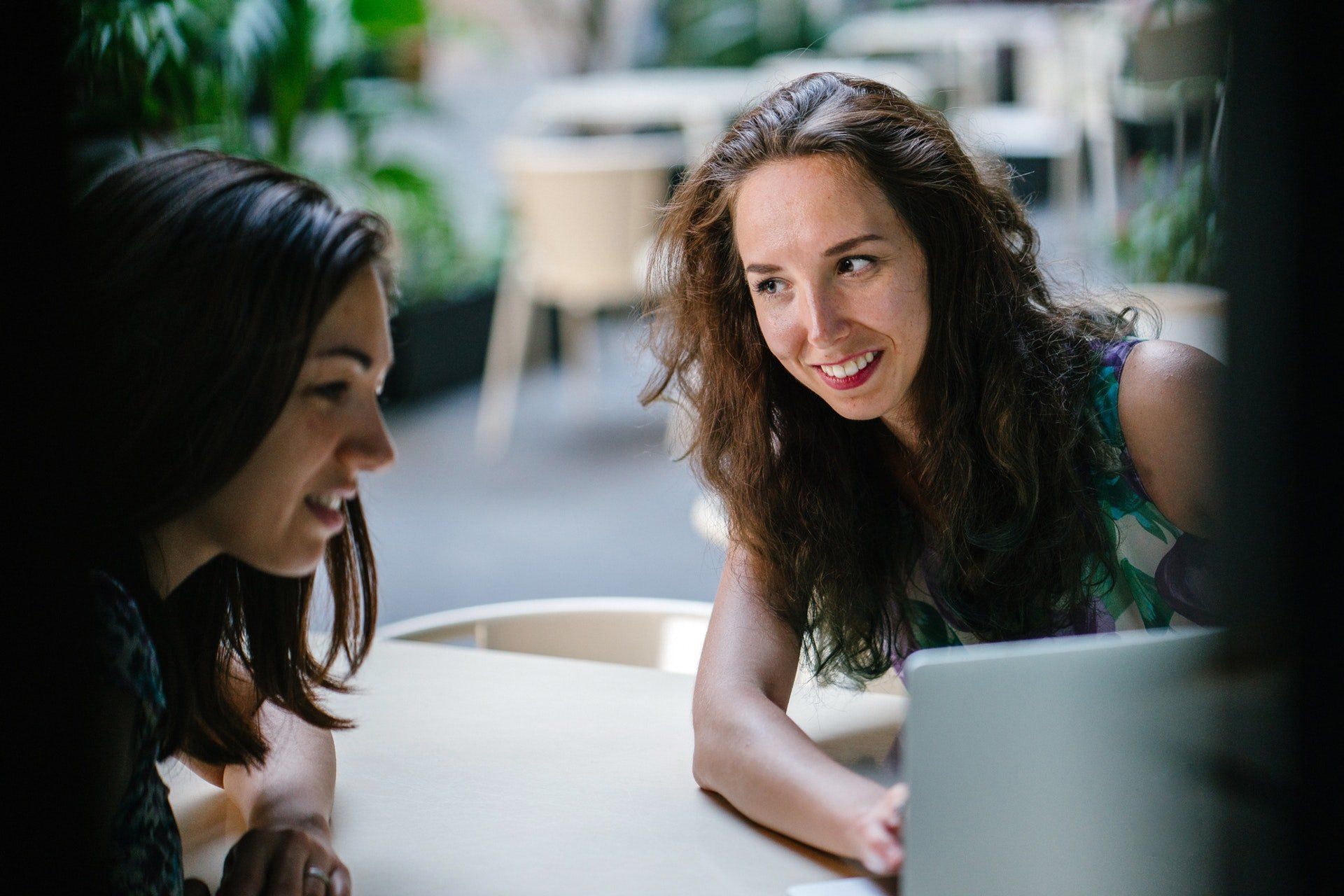 two talking women while using laptop