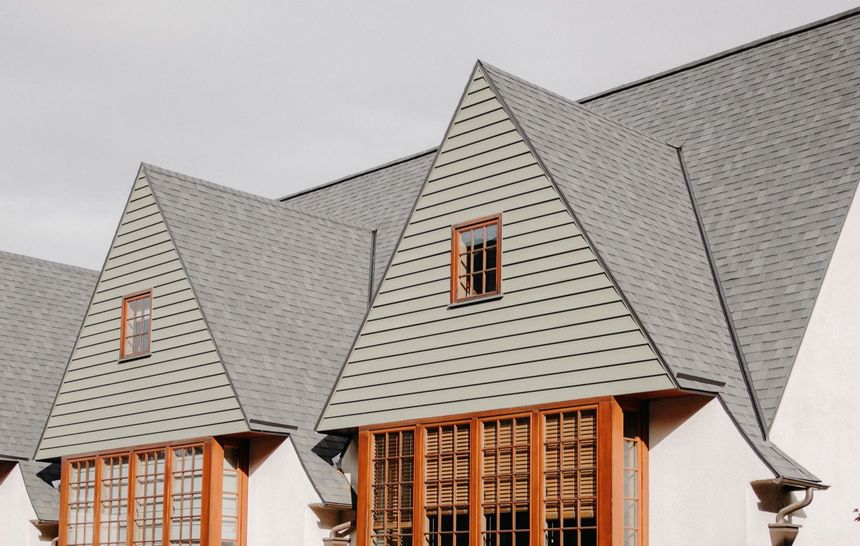 Gray house roofs with dormer windows and wood-trimmed gables under a bright sky