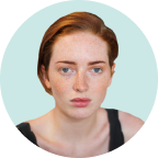 Portrait of a person with red hair and a neutral expression against a light blue background