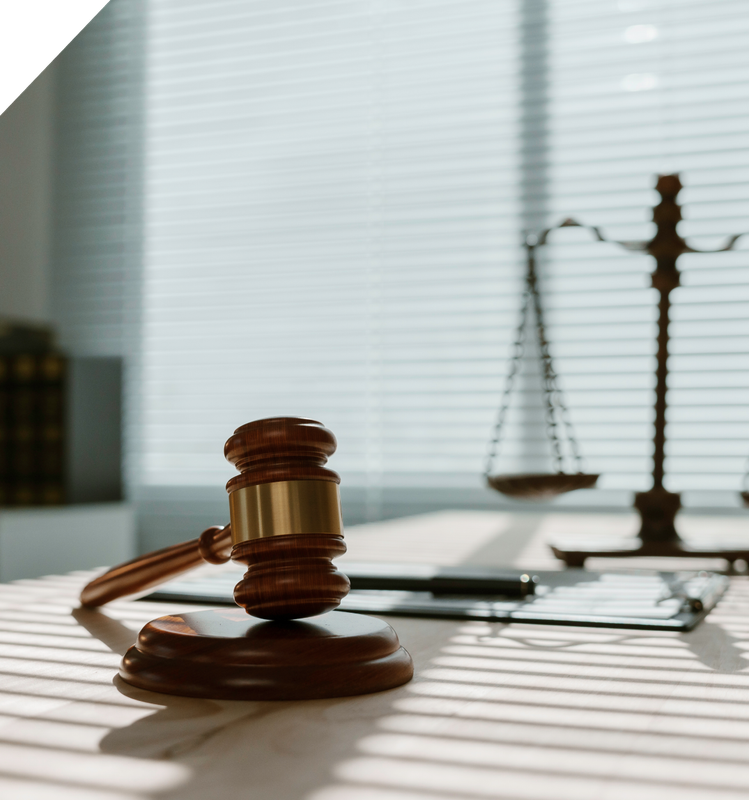 Judge’s gavel on a desk with a scale of justice and laptop in a sunlit law office