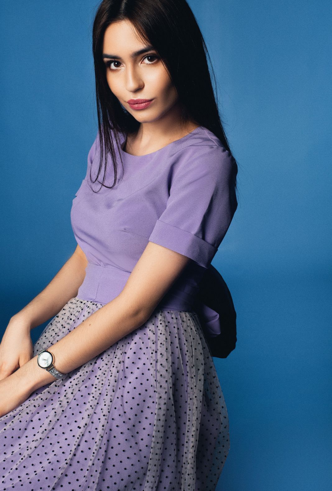 A woman in a purple dress is sitting on a blue surface.