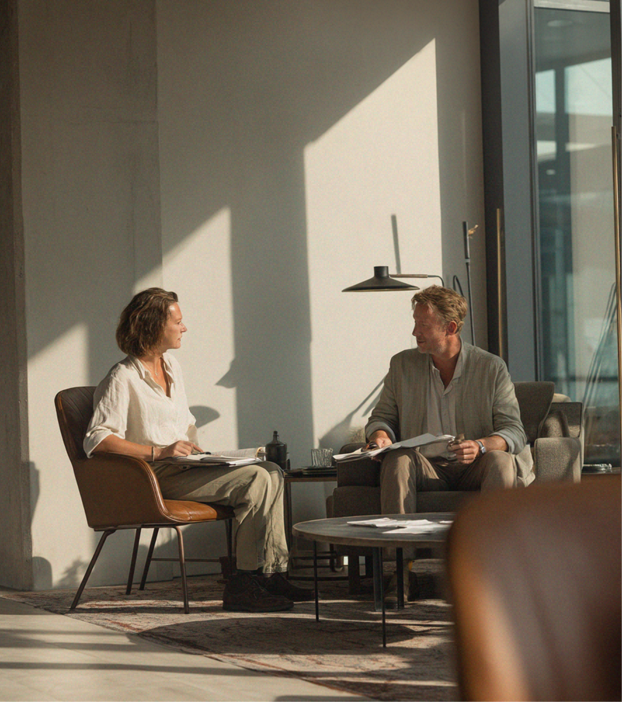 Two people sitting and talking in a sunlit modern living room