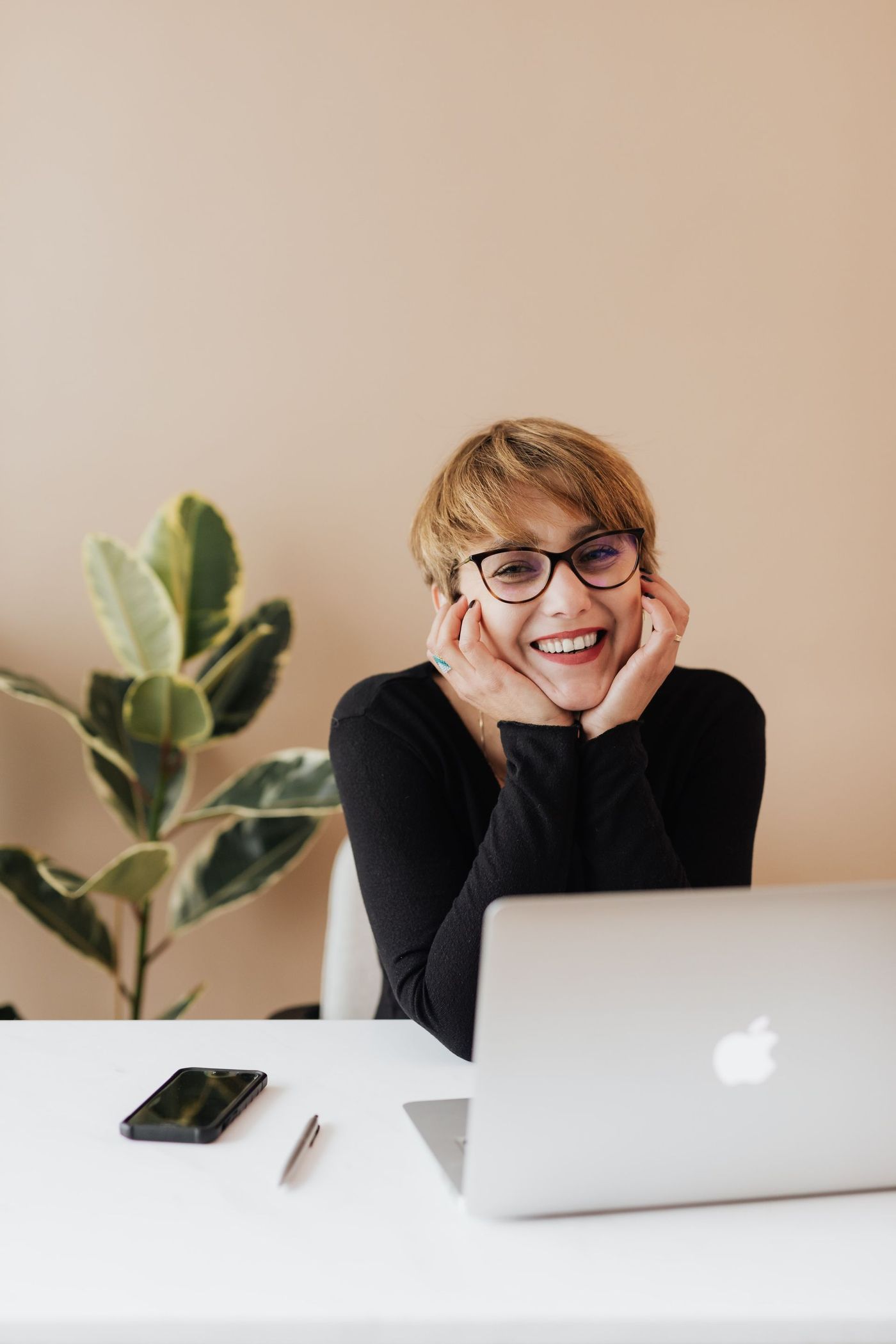 A woman is sitting at a desk with a laptop and smiling. Junk Guys LA call center is waiting for your inquiry like this.