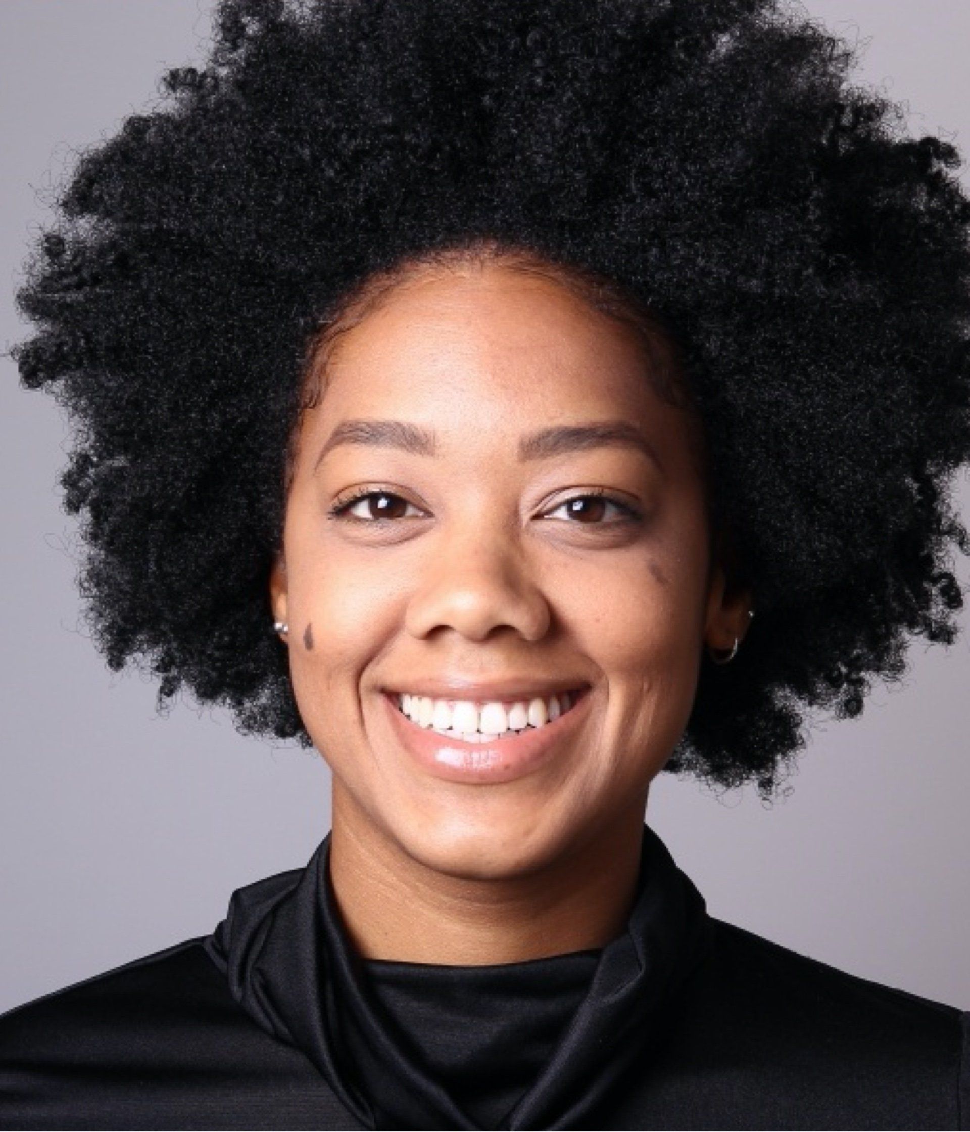 A woman with an afro is smiling and wearing a black shirt
